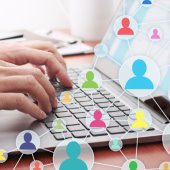 A hand types on a laptop keyboard. Graphic shows connected people.