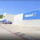 The exterior of Pelham's WalMart features a sign with white lettering spelling "WalMart" on a blue background with a  yellow sunburst logo.