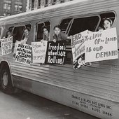 Historic photo shows Freedom Riders leaning out of a bus window while holding signs of protest
