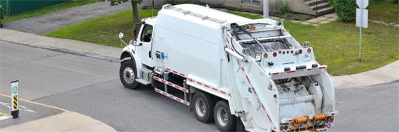 Garbage truck driving in a neighborhood to collect trash