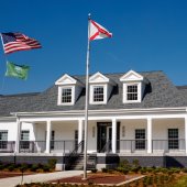The exterior of Pelham City Hall on a beautiful day with blue skies. Flags flying in front of the building.