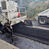 Heavy equipment resurfacing a city street.