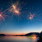 Fireworks explode over a beautiful mountain lake.
