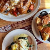 Various plates of breakfast foods sitting on a menu for Big Bad Breakfast restaurant.