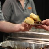 A participating vendor at Taste of Pelham 2022 offers a plate of food to an attendee.