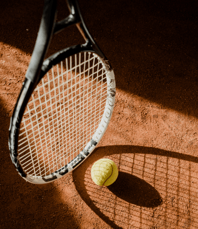 A tennis racquet and ball are shown on a dark court with a shaft of light highlighting them.